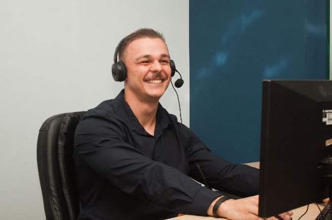 A smiling sales consultant on a call at his desk